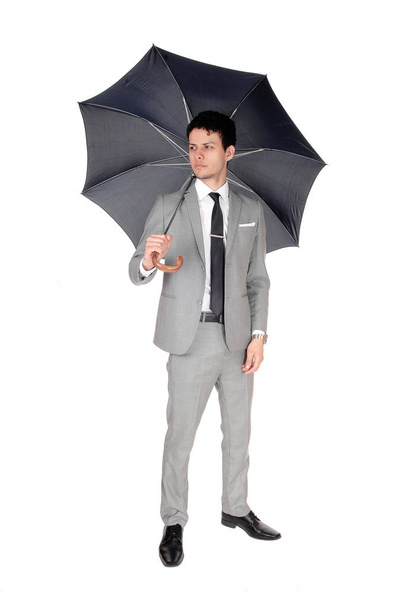 Um homem de negócios bonito jovem de pé em um terno cinza claro and.an guarda-chuva aberto, isolado para fundo branco
. - Foto, Imagem