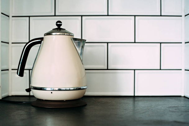 Металевий електричний чайник на білій плитці
 - Фото, зображення