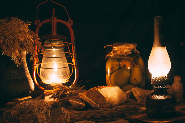 Domowej roboty pieczony chleb na drewnianej desce w ciepłym świetle z lamp gazowych. Rustykalne otoczenie vintage - Zdjęcie, obraz