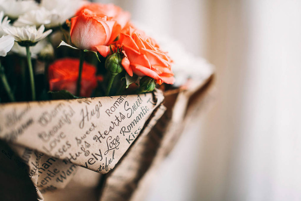 Bouquet of pink roses and white asters wrapped in paper. Close-up photo with copy space. - Zdjęcie, obraz