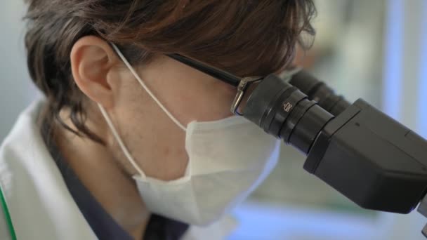 Scientist in a laboratory uses a microscope. Closeup shot - Materiaali, video
