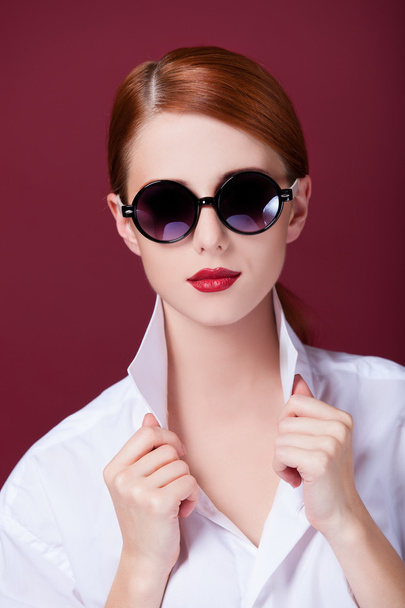 Redhead in sunglasses on red background - Valokuva, kuva