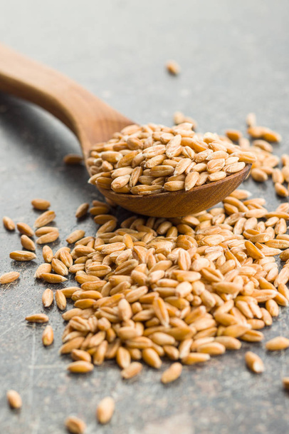 Healthy spelt grains in wooden spoon. - Photo, Image
