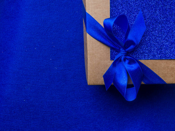festive gift wrapped present box with blue satin bow close up isolated on trendy blue background - Fotoğraf, Görsel