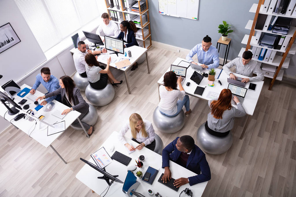 Група багатоетнічних бізнесменів сидять на фітнес м'яч обговорюючи під час роботи в офісі
 - Фото, зображення