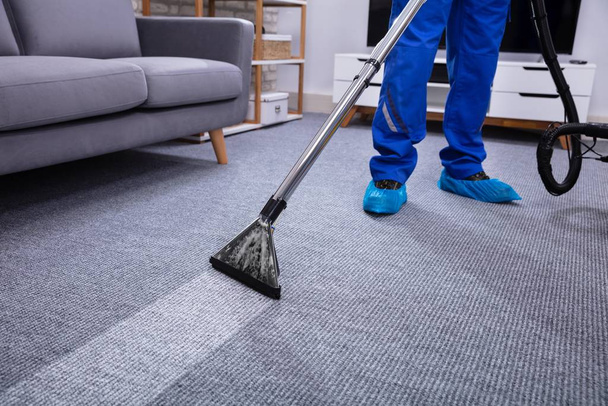 Low Section Of A Male Janitor Cleaning Carpet With Vacuum Cleaning In The Living Room - Foto, Imagem