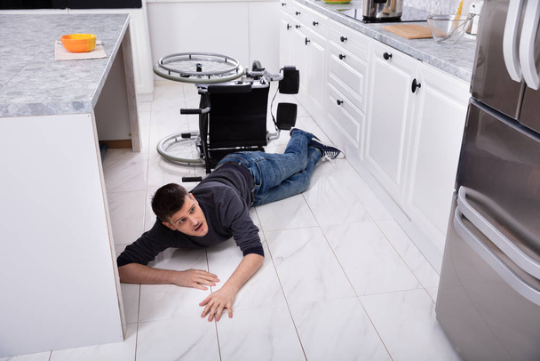 Fiatal fogyatékos férfi leesett a kerekesszékről a konyhában - Fotó, kép