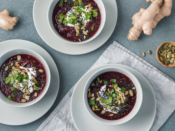 Ideas and recipes for healthy soup - Beetroot and ginger soup puree. Clean eating, detox, vegetarian diet concept. Top view of plate with perfect beet soup, dressed pepitas, sesame and parsley - Photo, image