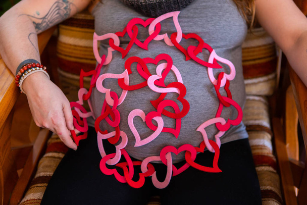 Zwangere vrouw en rode valentijn harten - Foto, afbeelding