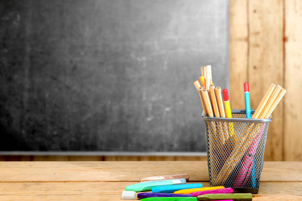 Pencils in basket container and colorful crayons on the wooden table with blackboard background. Back to School concept - 写真・画像