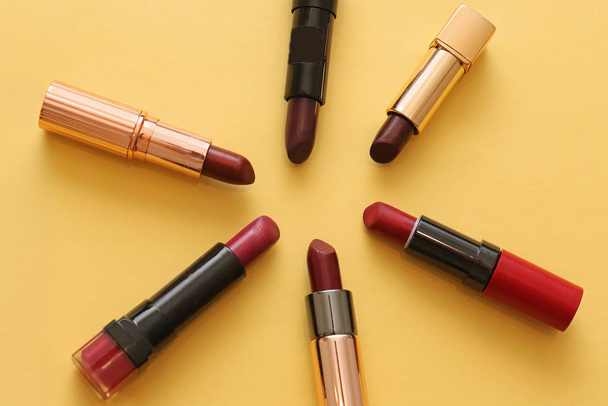 Shades of red lipsticks make up tubes on yellow background - Fotoğraf, Görsel