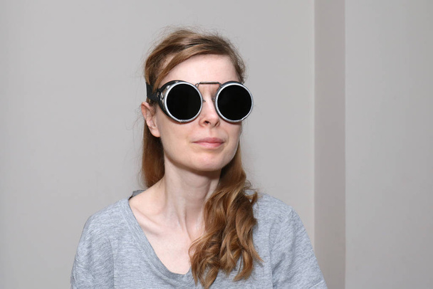 Young woman with pale face skin wearing black welding glasses - Фото, зображення