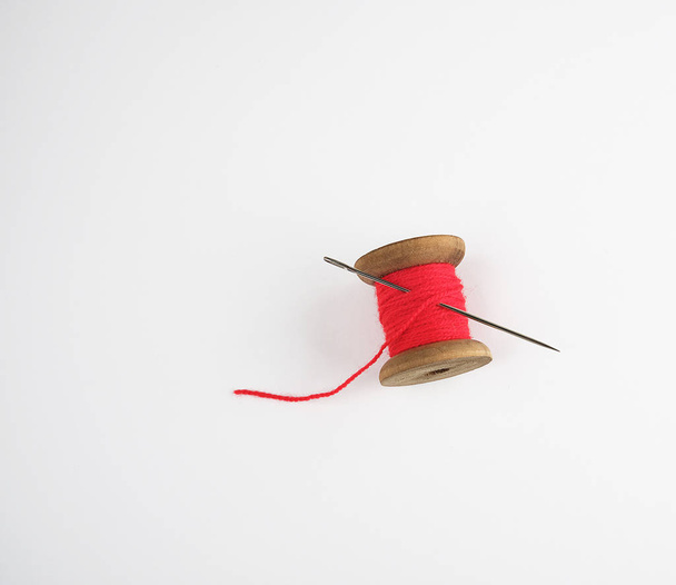 Enrouleur en bois avec fil de laine rouge et une grande aiguille, fond blanc, espace de copie
 - Photo, image