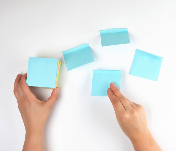 lot of empty blue stickers on a white background and two female hands, conceptual background - 写真・画像