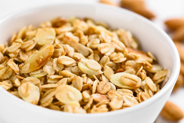 Homemade baked crunchy oatmeal, sliced almond, honey and coconut oil breakfast granola in bowl (Selective Focus, Focus in the middle of the granola) - Zdjęcie, obraz