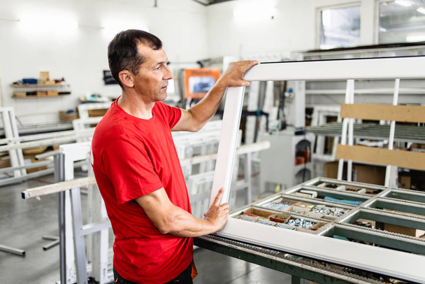 Manual worker assembling PVC doors and windows. Manufacturing jobs. Selective focus. Factory for aluminum and PVC windows and doors production. - Foto, Imagen