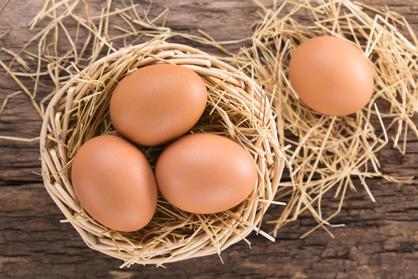 Fresh raw brown eggs on hay in basket, photographed overhead (Selective Focus, Focus on the top of the eggs in the basket) - 写真・画像