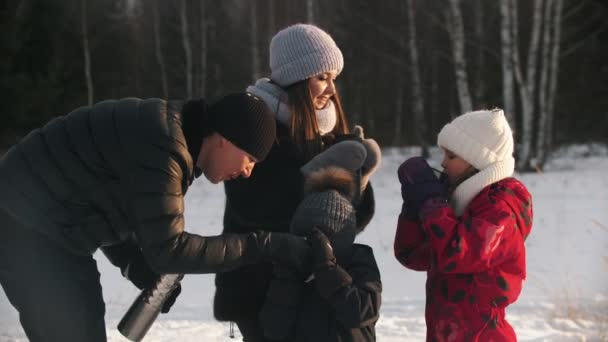 Ευτυχισμένη οικογένεια τεσσάρων ατόμων που πίνουν ζεστά ροφήματα από τα termos το χειμώνα - Πλάνα, βίντεο
