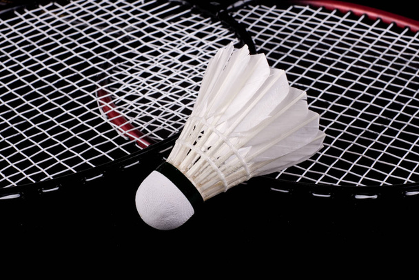 Shuttlecock and badminton racket over black background - Foto, imagen