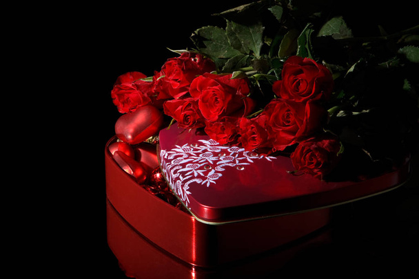 Heart-shaped red box and flowers on a black background. Valentine&#039 - Zdjęcie, obraz