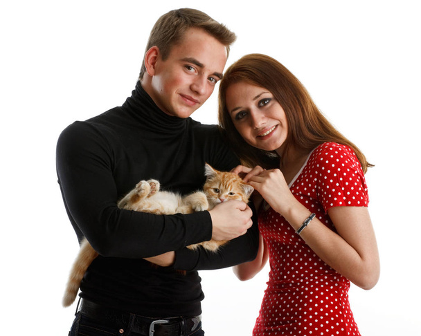 The happy young couple with a small amusing kitten on a white background. - Fotoğraf, Görsel