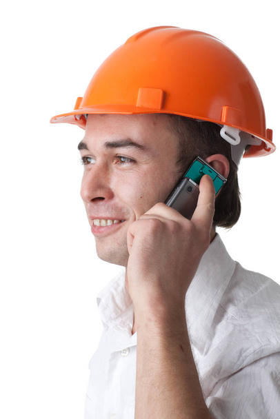 Male architect in a hard hat talks by a mobile phone on a white background. - Photo, Image