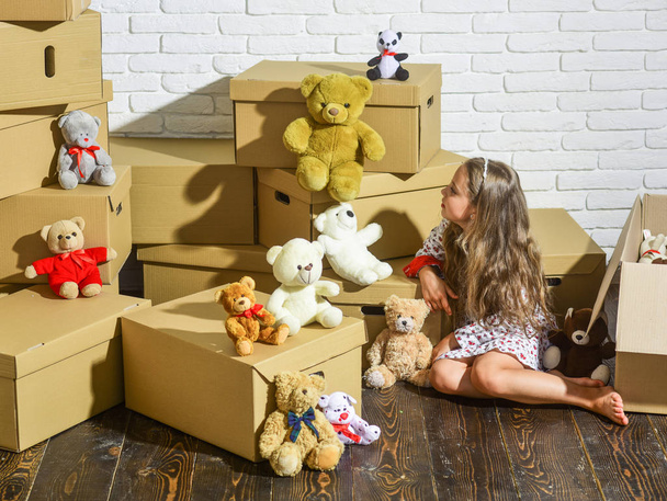 Playroom concept. Moving in. Delivering service. Feeling good at home. All she needs are toys. Home is where are my toys. Teddy bear collection. Sweet home. Girl child relaxing after unpacking boxes - Photo, image