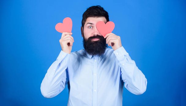 Man bearded hipster with heart valentine card. Celebrate love. Guy attractive beard and mustache in romantic mood. Feeling love. Dating and relations concept. Making man feel loved. Happy in love - Фото, изображение