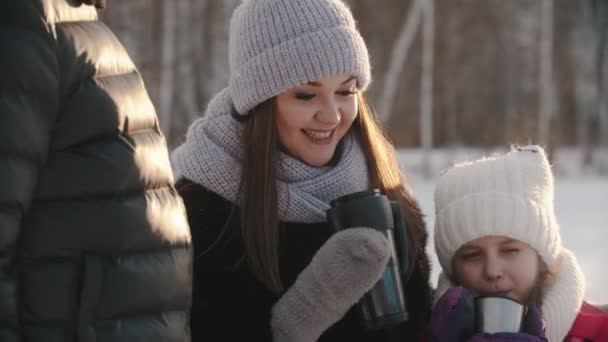 Οικογένεια τεσσάρων ατόμων που πίνουν ζεστά ροφήματα από το termos το χειμώνα - ένα μικρό κορίτσι που γελάει - Πλάνα, βίντεο