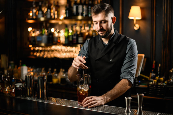 Male bartender stirring alcohol cocktail with bar spoon - Фото, зображення