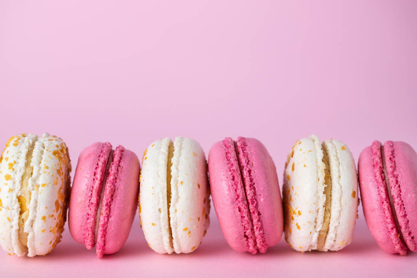 French delicious pink and white macarons of different flavors on pink pastel background. - Photo, Image