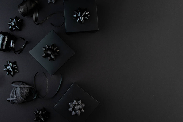 Minimalist black flat lay. Black gift boxes with ribbons on black surface, black friday concept, gift for man, father, husband. - Foto, afbeelding