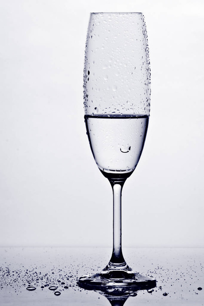 wet champagne glass with drops contrasting against white ground with reflection on floor - Foto, immagini