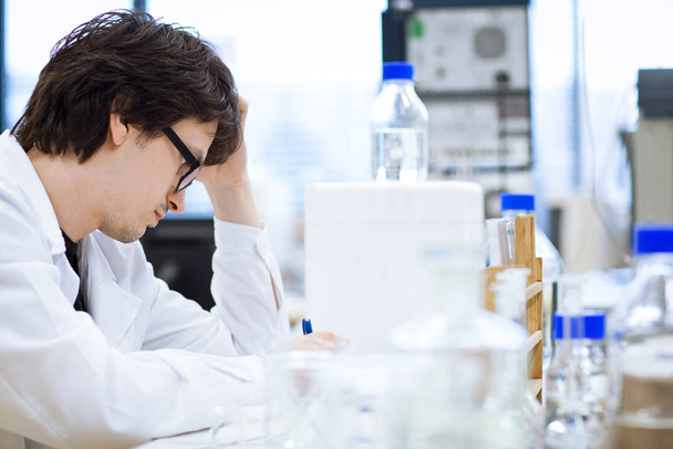 young male researcher/chemistry student carrying out scientific research in a laboratory (shallow DOF - Photo, Image