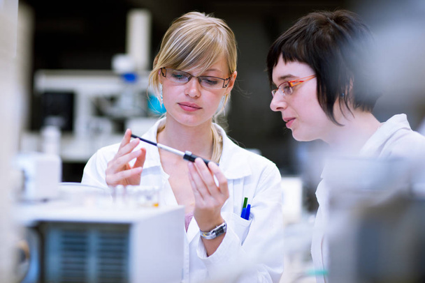 twee vrouwelijke onderzoekers / scheikundestudenten doen onderzoek in een scheikundelab (verkleurd beeld - Foto, afbeelding