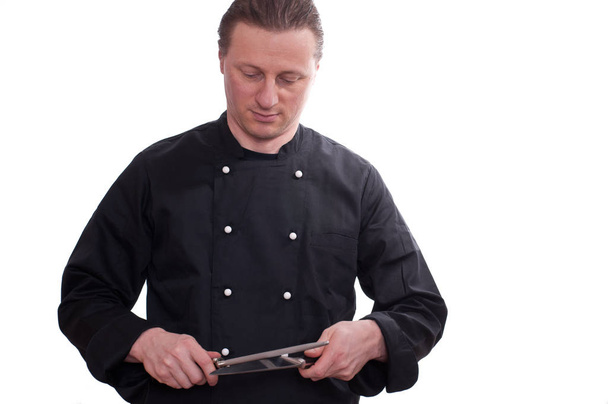 een man als kok doet een mes op een slijpen staal te scherpen - Foto, afbeelding