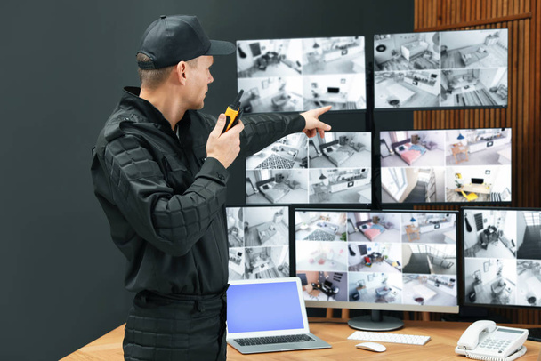 Security guard with portable transmitter monitoring modern CCTV  - Valokuva, kuva