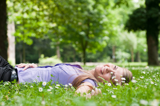 Detail of young woman lying in fresh green grass with flowers - low angle view - Foto, Imagen