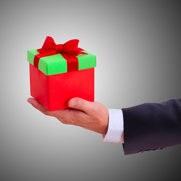 businessman holding gift box with red bow - Zdjęcie, obraz