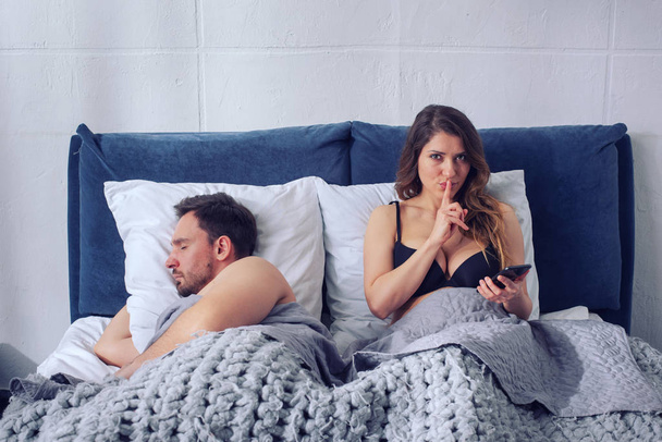 Girlfriend secretly chatting with others while he sleeps. Infidelity concept - Photo, Image