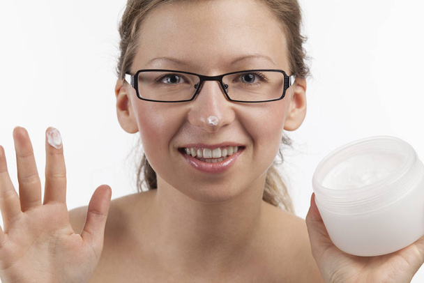cheerful young woman with cosmetic care product - 写真・画像