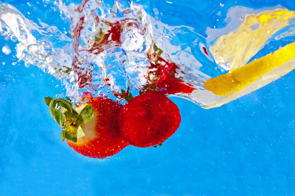 青いモザイクの背景に新鮮な果物が水に落ちる - 写真・画像