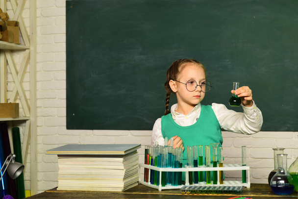What is taught in chemistry. Chemistry science. Child in the class room with blackboard on background. Child from elementary school. - Foto, imagen