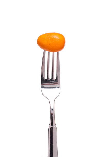 an orange kumquat and a fork against white background - Foto, afbeelding