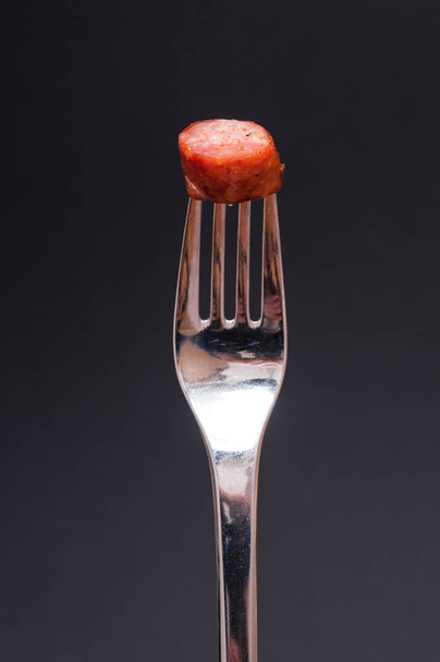 sausage and a fork against black background - Fotografie, Obrázek
