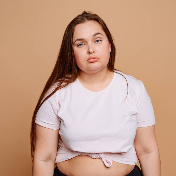 Lazy overweight woman on beige background. Unhealthy lifestyle - Photo, image
