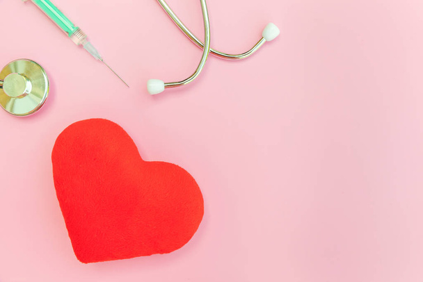 Lääkinnälliset laitteet stetoskooppi tai fonendoskooppi ruisku ja punainen sydän eristetty trendikäs pastelli vaaleanpunainen tausta
 - Valokuva, kuva