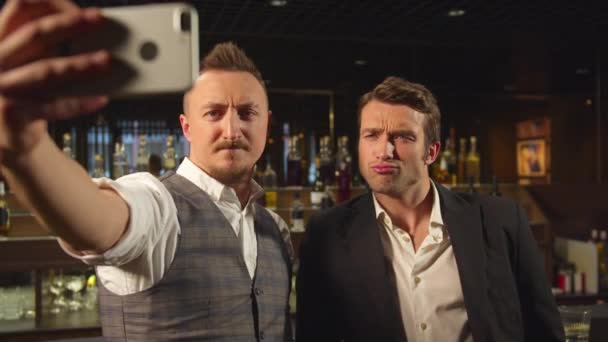 Kaksi miestä seisoo baarissa ja tekee selfien puhelimessa
 - Materiaali, video