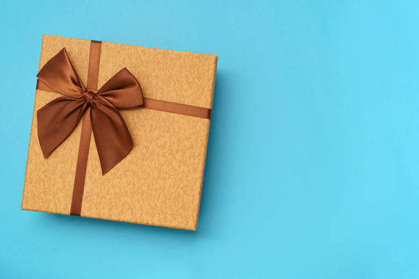 Brown gift box with brown  ribbon isolated on blue background - Fotoğraf, Görsel