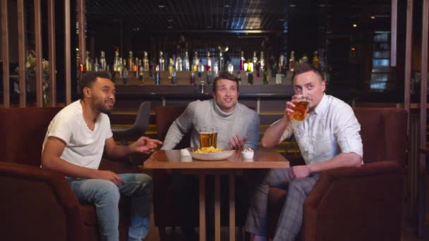 Slow motion, friends sit at the bar, drink beer and watch footbal - Video, Çekim